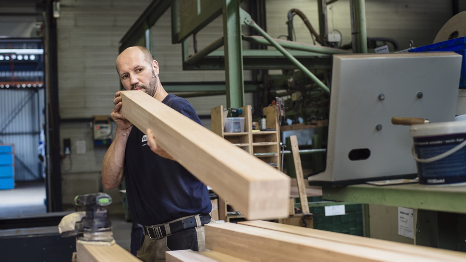 Van De Vin Ramen en Kozijnen in Heeze Medewerker Van De Vin Ramen en Kozijnen die hout aan het bewerken is in de fabriekshal.