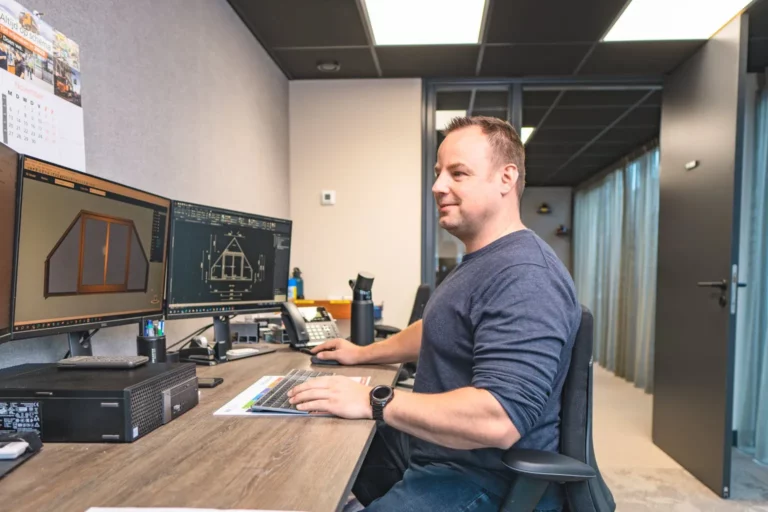 Man achter computer met drie schermen en bezig met 3D tekenen | HOUT100%