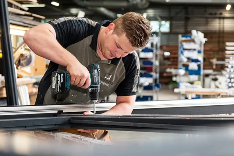 Man met boormachine dat een gat boort in een kozijn | HOUT100%